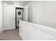 Hallway view of the laundry closet with stacked washer and dryer, adjacent to white railings at 7856 W 43Rd Pl, Wheat Ridge, CO 80033
