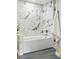 Bright bathroom features modern white and gray marble tile with white tub and shower combo at 10320 W 35Th Ave, Wheat Ridge, CO 80033