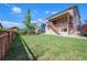 Spacious backyard with a deck, a wooden fence, a shed, and a lush green lawn at 6147 N Flanders St, Aurora, CO 80019