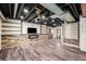 Spacious basement with rustic wood flooring, custom shelving, and a modern fireplace at 6147 N Flanders St, Aurora, CO 80019