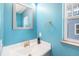 Stylish powder room featuring bright turquoise walls, modern sink and fixtures, and ample natural light at 6147 N Flanders St, Aurora, CO 80019