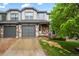 Charming townhome featuring stone accents, gray siding, attached garage, and landscaped front yard at 2002 E 102Nd Cir, Thornton, CO 80229