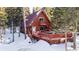 Aerial view of A-frame cabin, deck, and hot tub in snow at 381 Lake Rd, Idaho Springs, CO 80452