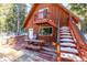 Cabin deck with picnic table, stairs, and snowy surroundings at 381 Lake Rd, Idaho Springs, CO 80452