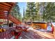 Deck with hot tub, picnic table, and surrounding snowy trees at 381 Lake Rd, Idaho Springs, CO 80452