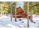 A-frame cabin with wrap-around deck and hot tub, nestled in a snowy wooded area at 381 Lake Rd, Idaho Springs, CO 80452