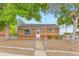 Charming single-story brick home featuring a well-kept front yard and a secure chain-link fence at 6930 Warren Dr, Denver, CO 80221
