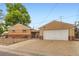 Exterior view featuring the garage door, connecting patio, and quaint brick siding at 6930 Warren Dr, Denver, CO 80221