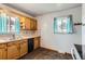 Functional kitchen featuring wooden cabinets, tile backsplash, and a sink with a window view at 6930 Warren Dr, Denver, CO 80221