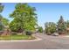 Street view featuring mature trees, landscaped yard, and neighborhood street with parked cars at 6930 Warren Dr, Denver, CO 80221