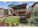 Exterior shot showcasing backyard, patio, deck and landscaping with a green lawn, trampoline, and stairs at 8107 Arapahoe Peak St, Littleton, CO 80125