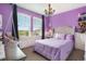 Vibrant purple bedroom with hanging chair, chandelier, and large windows overlooking the neighborhood at 8078 S Yantley Ct, Aurora, CO 80016