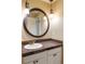 Bathroom featuring a round mirror over a white sink and stylish lighting fixtures at 3765 S Depew St, Denver, CO 80235