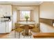 Bright kitchen with white appliances and a cozy breakfast nook with a round table and four chairs at 3765 S Depew St, Denver, CO 80235