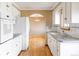 Bright kitchen features white appliances, white cabinetry, tile backsplash, and hardwood floors at 3765 S Depew St, Denver, CO 80235