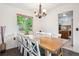 Dining area with wooden table, white chairs, chandelier, and a view to the kitchen at 5987 W Ken Caryl Pl, Littleton, CO 80128