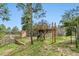 Backyard recreation area with wooden play structure, climbing wall, and mature trees at 1185 Fawnwood Rd, Monument, CO 80132