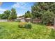 Spacious backyard with mature trees and lawn enclosed by a wooden fence at 2180 S Flower Way, Lakewood, CO 80227
