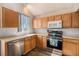 Well-lit kitchen with wooden cabinetry, stainless steel appliances, and a window over the sink at 1624 Westin Dr, Erie, CO 80516