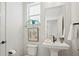 A pedestal sink and toilet are featured in this half bathroom with a sunlit window and tasteful botanical art at 16637 Shoshone St, Broomfield, CO 80023
