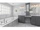Bright bathroom featuring a soaking tub, marble tile, and dual vanity sinks, with natural light from glass block window at 2370 W 152Nd Ave, Broomfield, CO 80023
