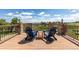 Outdoor deck featuring stone pillars, dark railings, and relaxing Adirondack chairs set against a backdrop of blue skies and countryside at 2370 W 152Nd Ave, Broomfield, CO 80023