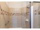 Bathroom with a tiled shower, decorative border, showerhead, and grab bar enhances accessibility and style at 10581 Pearlwood Cir, Highlands Ranch, CO 80126