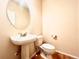 A half bath featuring a pedestal sink, round mirror, and toilet with a wood-look floor at 3155 E 104Th Ave # 4E, Thornton, CO 80233