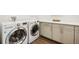 Modern laundry room with front load washer and dryer, storage cabinets and hardwood floors at 2027 Vallejo Loop, Broomfield, CO 80023