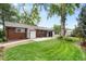 Expansive backyard with lush green lawn, mature trees, and the back of a brick home with a patio at 32 Skyline Dr, Wheat Ridge, CO 80215