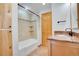 Bathroom boasts a shower and bathtub, wooden cabinets and a sink at 32 Skyline Dr, Wheat Ridge, CO 80215
