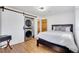 Bright bedroom features wood floors, barn door closet with stackable washer/dryer, and adjacent bathroom at 32 Skyline Dr, Wheat Ridge, CO 80215