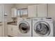 Functional laundry room with modern washer and dryer, sink, storage cabinets, and natural light at 5625 S Buchanan St, Aurora, CO 80016