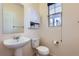 Cozy half bathroom featuring a pedestal sink, toilet, and medicine cabinet above toilet at 8562 E 49Th Pl, Denver, CO 80238