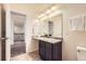 Bathroom featuring single vanity and decorative lights, adjacent to carpeted hallway at 8562 E 49Th Pl, Denver, CO 80238