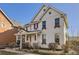 Side view of a charming white two-story home with a welcoming front porch under a clear blue sky at 8562 E 49Th Pl, Denver, CO 80238