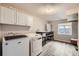 Laundry room with white washer and dryer, overhead cabinets, and vinyl floors at 3416 Hawthorne Dr, Highlands Ranch, CO 80126