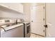 A laundry room with front loading washer and dryer, white cabinets, and a tiled floor at 3416 Hawthorne Dr, Highlands Ranch, CO 80126
