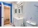 Modern bathroom featuring white marble-look tile, a white vanity with storage, and a blue accent doorway at 4234 S Bahama St, Aurora, CO 80013