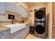 Laundry room with farmhouse sink, modern stacked washer and dryer at 4812 Moonshine Ridge Trl, Parker, CO 80134