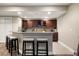 Basement bar with counter seating and dark wood cabinets for wine and glasses at 1775 Catnap Ln, Monument, CO 80132