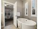 Bright bathroom featuring a soaking tub with elegant fixtures and a glimpse of the bedroom through the doorway at 1775 Catnap Ln, Monument, CO 80132