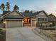 Inviting exterior view showcasing a two-car garage, stylish stonework, and well-manicured landscaping at 1775 Catnap Ln, Monument, CO 80132