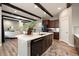 Open-concept kitchen with an island, dark wood cabinets, and hardwood floors, flowing into the living room at 1775 Catnap Ln, Monument, CO 80132