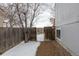 Fenced backyard with gated access and gray home exterior during winter at 12425 Albion St, Thornton, CO 80241