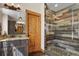Elegant bathroom features a glass shower with stone accents and granite countertops with modern dark wood cabinets at 5800 Elk View Ct, Larkspur, CO 80118