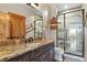Stylish bathroom highlighting a beautifully tiled shower, granite countertop, and dark wood vanity at 5800 Elk View Ct, Larkspur, CO 80118
