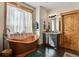Bathroom featuring a copper soaking tub, wood accents, and natural light at 5800 Elk View Ct, Larkspur, CO 80118