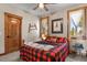 Cozy bedroom with a buffalo plaid comforter, natural wood accents, and bright natural light at 5800 Elk View Ct, Larkspur, CO 80118