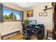 Home office with wood floors, desk setup with computer, and a window with view of green trees at 9598 Lowell Blvd, Westminster, CO 80031